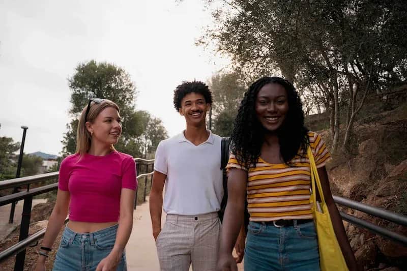 Three adult students walking outdoors in Barcelona, smiling and enjoying their time together.