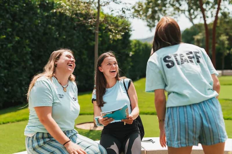 An Expanish summer camp staff member and a student share a joyful moment outdoors in Barcelona, while another staff member stands nearby.