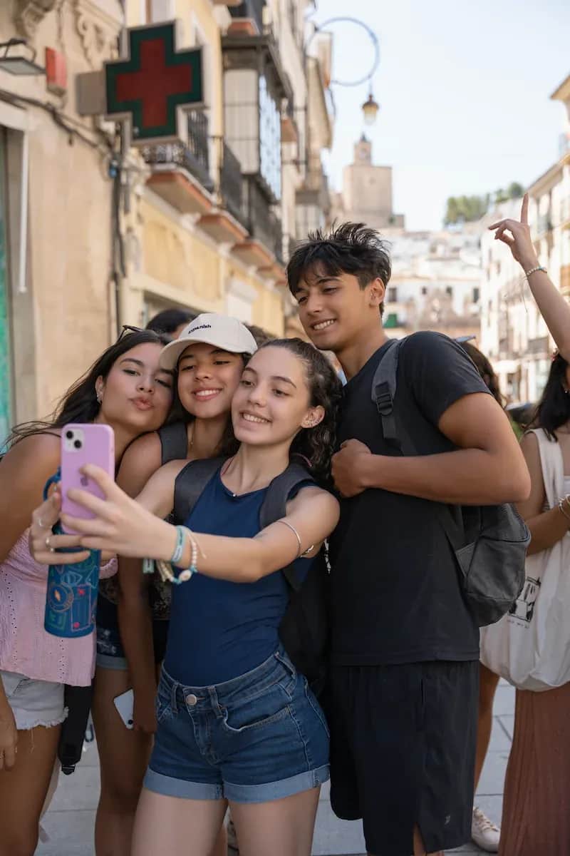 A group of Expanish summer camp students in Barcelona smiling and taking a selfie together while exploring the city streets.